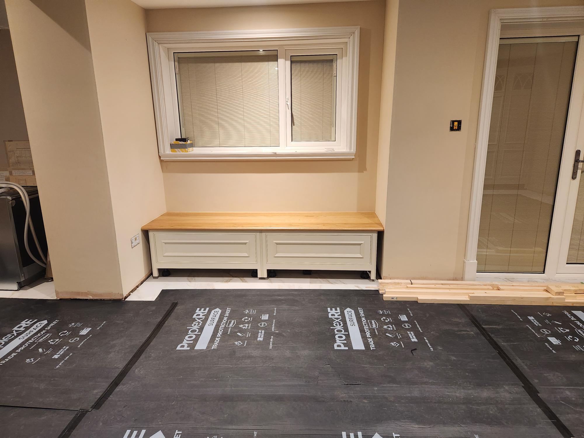 Fitted window seat with oak top and cream panelled storage