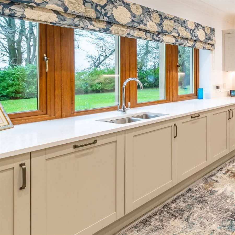 Kitchen sink run with floral roman blind and countryside views