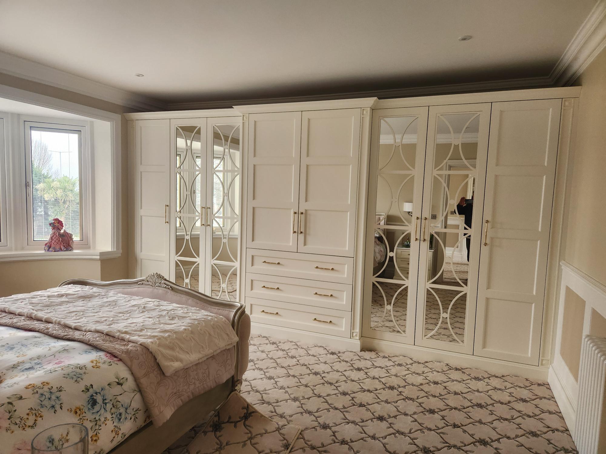 Luxury white fitted wardrobes with oval fretwork mirrored doors