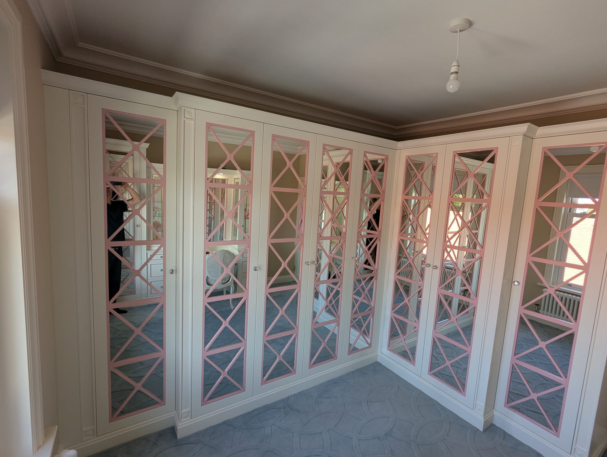 Corner fitted wardrobes with decorative pink lattice mirrored doors